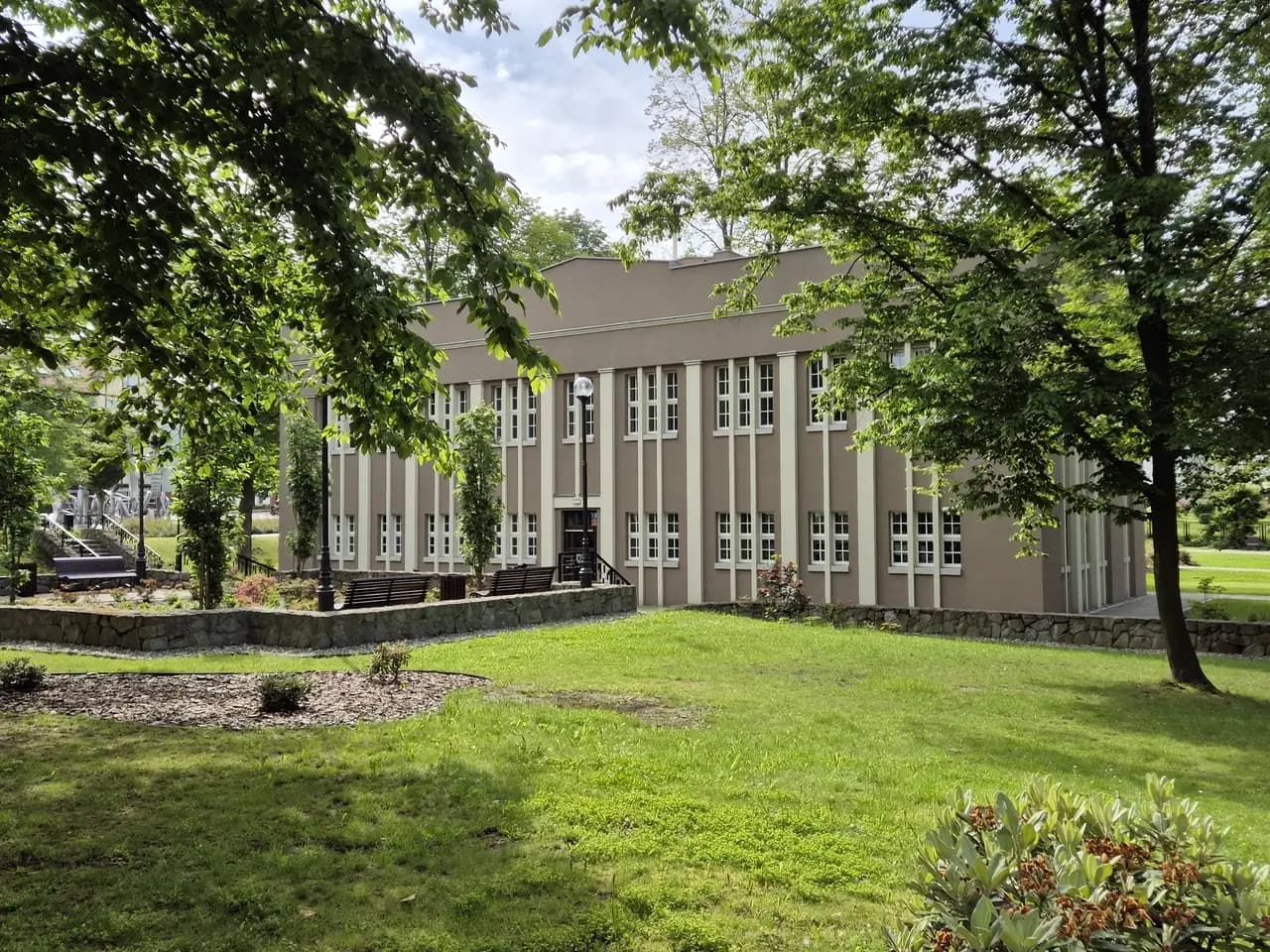 Modernistyczny budynek Łazienek III w jastrzębskim Parku Zdrojowym, otoczony zielenią